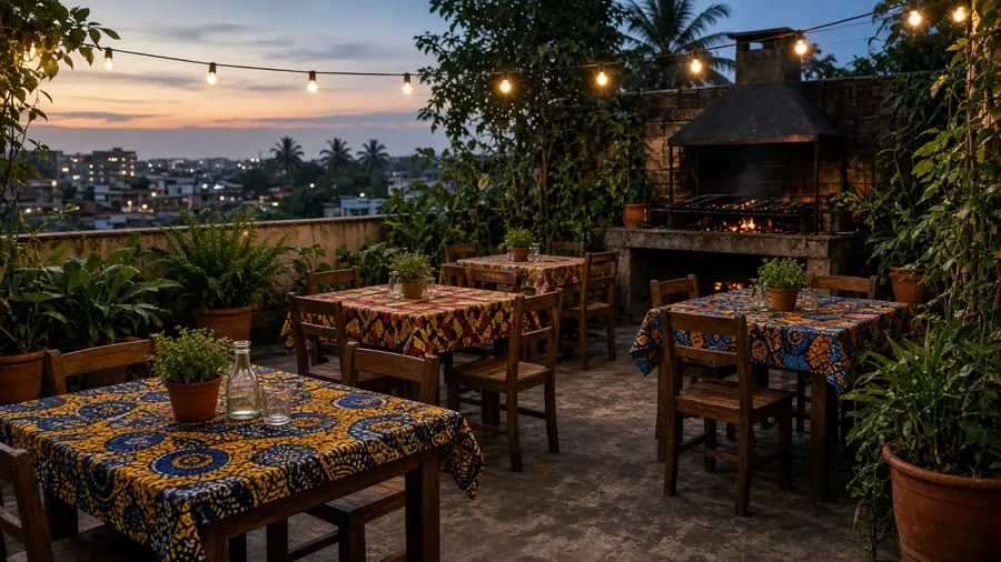 Terrasse du restaurant le soir, tables en pagne et grill au feu de bois